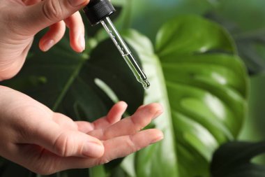 Kadın arka plandaki bulanık parmağa kozmetik serumu uyguluyor. Yakın plan. Metin için boşluk