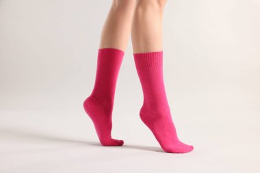 Açık gri arka planda parlak pembe çoraplı kadın, yakın plan.