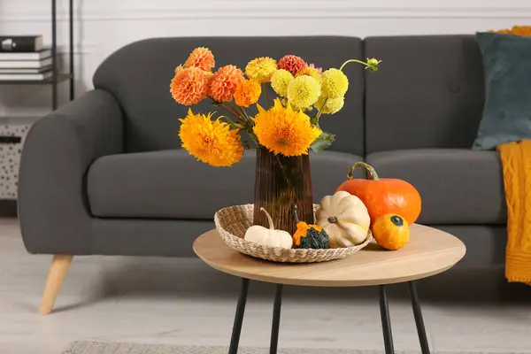 Beautiful autumn bouquet and pumpkins on coffee table near sofa in room