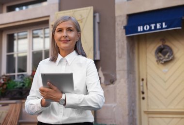 Otelinin yanında tableti olan mutlu bir işyeri sahibi, mesaj atmak için yeri var.
