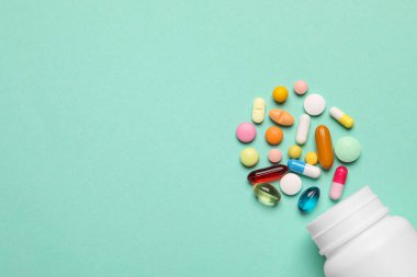 Turkuaz arka planda bir sürü farklı ilaç içeren plastik tıbbi şişe, düz yatak. Metin için boşluk