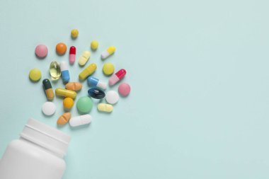 Açık mavi arka planda bir sürü farklı hap bulunan plastik şişe, düz yatıyordu. Metin için boşluk