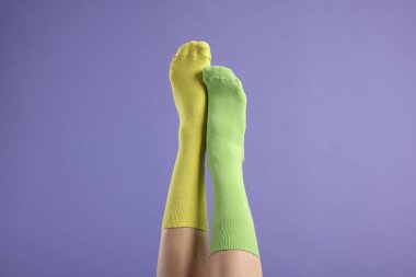 Mor arka planda farklı tarz çoraplar giyen kadın, yakın plan.