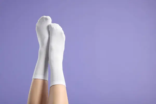 Woman in stylish white socks on violet background, closeup. Space for text