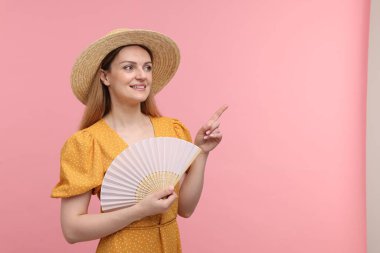 Pembe arka planda el yelpazesi olan mutlu kadın.
