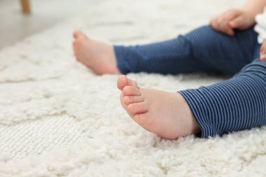 Bebek içeride yumuşak halıda oturuyor, yakın plan. Metin için boşluk