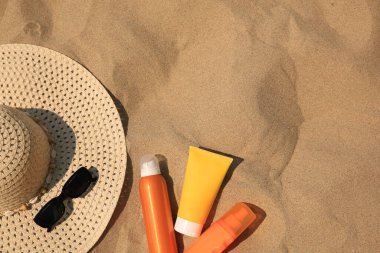 Kum üzerinde güneş kremleri olan düz bir kompozisyon, metin için boşluk. Güneş koruma servisi