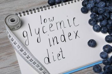 Sözcüklerle dolu bir defter Düşük Glisemik Diyet, bant ve böğürtlen ölçümü açık ahşap masa, yakın plan