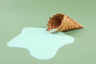 Eritilmiş dondurma ve yeşil arka planda gofret konisi, yakın plan.