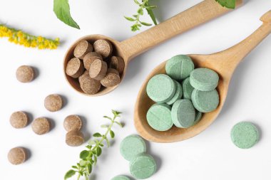 Beyaz arka planda farklı haplar ve bitkiler var. Beslenme takviyeleri