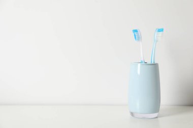 Beyaz masadaki tutucuda plastik diş fırçaları, metin için boşluk