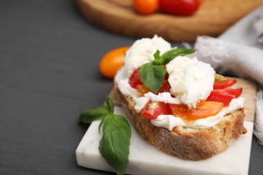 Burrata peynirli lezzetli sandviç ve gri ahşap masadaki domatesler, yakın plan. Metin için boşluk