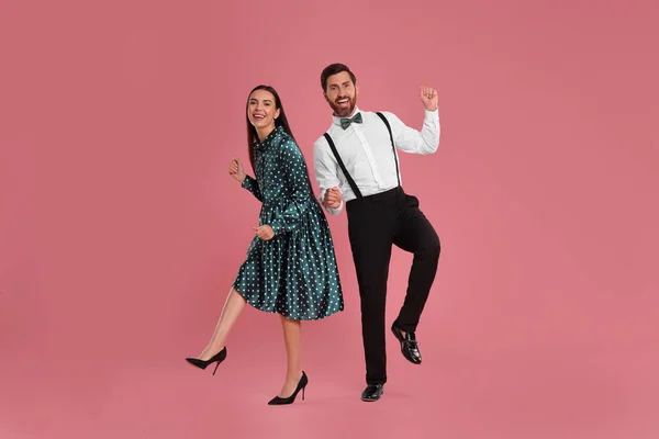 Happy couple dancing together on pink background
