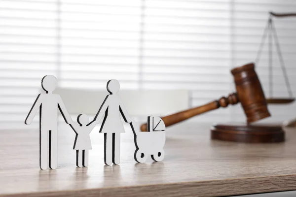 Family law. Figure of parents with children and gavel on light wooden table, space for text