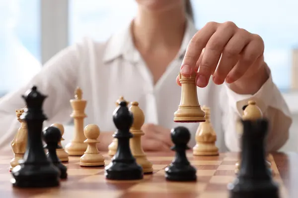 Woman playing chess during tournament at chessboard, closeup