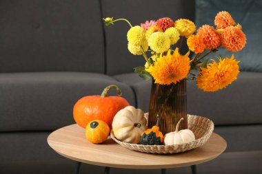 Oda odasındaki kanepenin yanındaki kahve masasında güzel bir sonbahar buketi ve balkabakları.