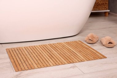Bambu banyo paspası ve banyoda yerde terlikler.