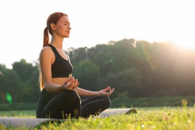 Güzel genç bir kadın yoga minderinde Padmasana egzersizi yapıyor. Düşük açılı görüş ve mesaj için yer. Lotus pozu