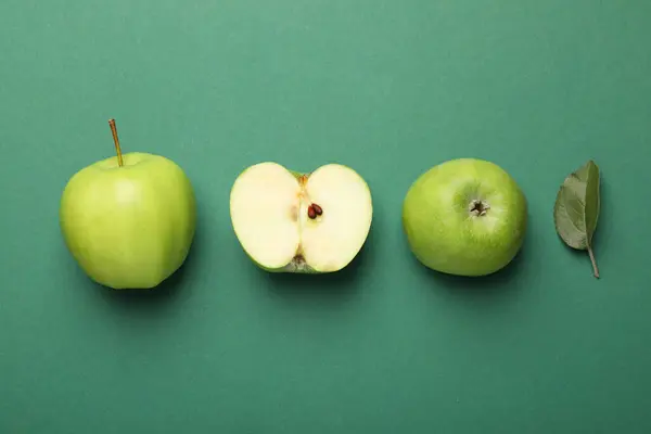 Whole, cut green apples and leaf on color background, flat lay