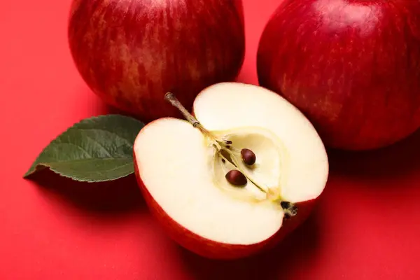 Whole, cut red apples and green leaf on color background, closeup