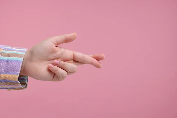 Woman crossing her fingers on pink background, closeup. Space for text