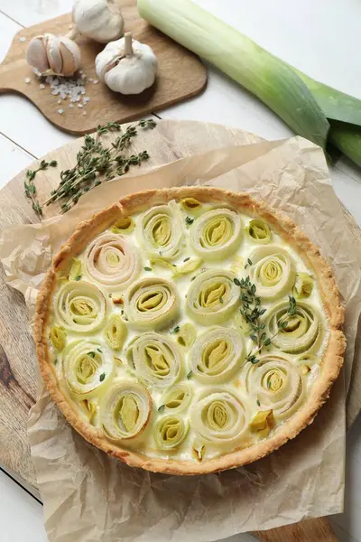 Tasty leek pie and products on white wooden table, above view