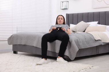 Kadın evde dar kot pantolon giymeye çalışıyor.