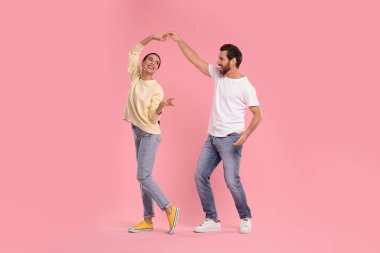 Mutlu çift pembe arka planda dans ediyor.