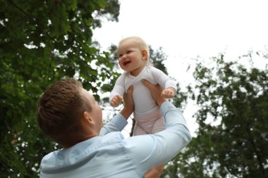 Babası sevimli bebeğiyle dışarıda vakit geçiriyor, düşük açılı.