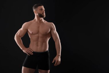 Siyah arka planda şık iç çamaşırlı genç bir adam. Metin için boşluk