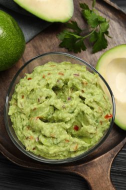 Maydanozlu guacamole ve ahşap masada taze avokado.