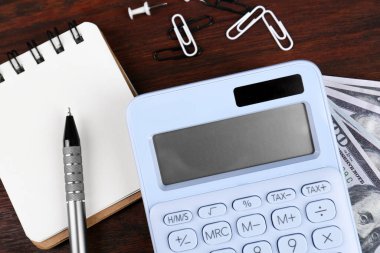 Hesap makinesi, defter, kalem, ataç ve dolar banknotları ahşap masa, düz yatak. Emeklilik kavramı