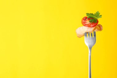 Dilimlenmiş jambonlu çatal, sarı arka planda domates ve maydanoz, mesaj için yer