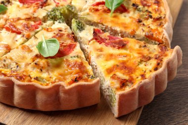 Domatesli kiş, fesleğen ve peynir ahşap masada, yakın plan.