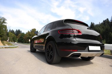 Asfalt yolda park edilmiş modern siyah araba.