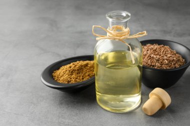 Tohumlar (Farsça kimyon) tohum, toz ve temel yağ gri masa üzerinde, yakın çekim