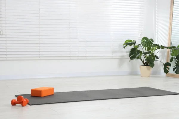 Exercise mat, yoga block and dumbbells at home. Space for text
