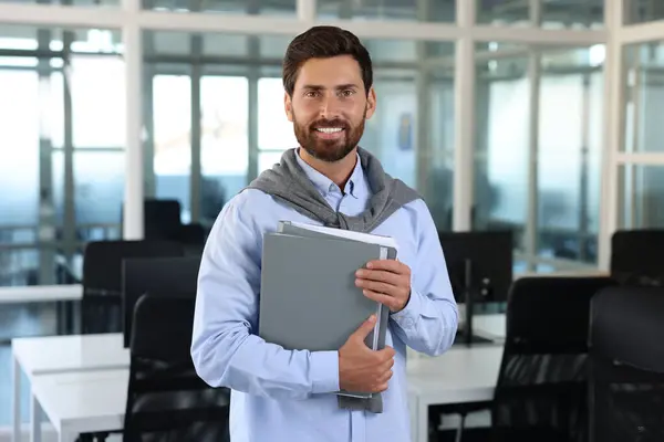 Handsome happy man with folders in office