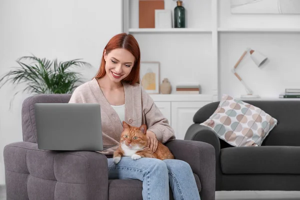 Happy woman with cat working in armchair at home, space for text