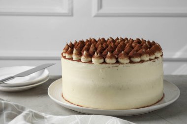 Açık gri desenli masada servis edilen kakao tozlu nefis tiramisu keki.