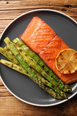 Ahşap masada kuşkonmaz ve limonlu ızgara somon.