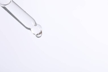 Beyaz arkaplandaki pipetten kozmetik serumu damlatılıyor, metin için boşluk