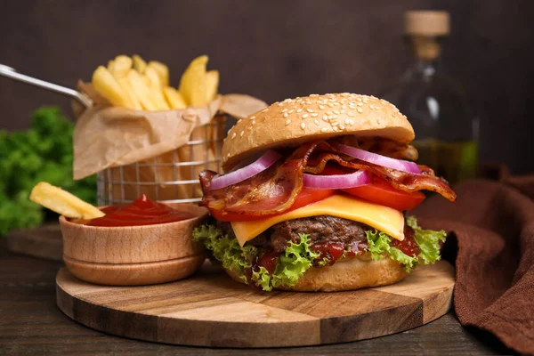 Tasty burger with bacon, vegetables and patty served with french fries and ketchup on wooden table