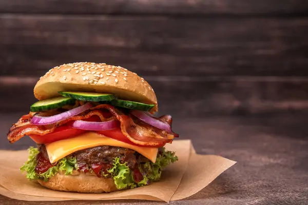 Tasty burger with bacon, vegetables and patty on textured table, space for text