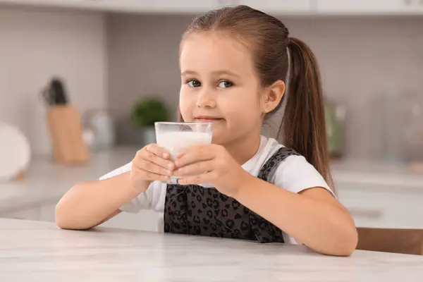 キッチンのホワイトテーブルでミルクのガラスとかわいい少女 — ストック写真