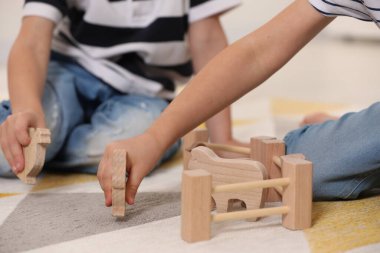 Little children playing with set of wooden animals indoors, closeup clipart