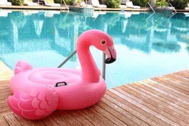 Lüks bir tatil köyünde yüzme havuzunun yanındaki tahta güvertede flamingo şeklinde süzül.