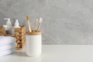 Beyaz tezgahta tutacakta bambu diş fırçaları, havlular ve kozmetik ürünler, metin için boşluk