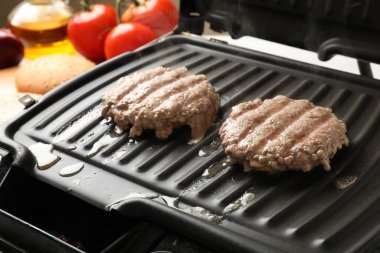 Lezzetli hamburger köfteleri elektrikli ızgarada pişiyor, yakın plan.