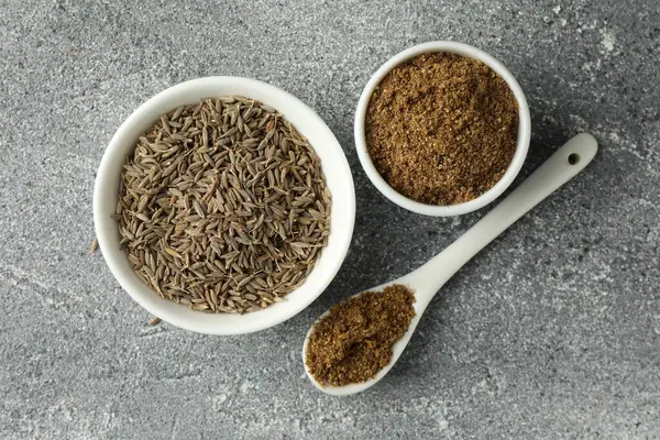 stock image Caraway (Persian cumin) seeds and powder on light gray textured table, flat lay